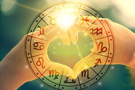 Heart hands over a zodiac wheel
